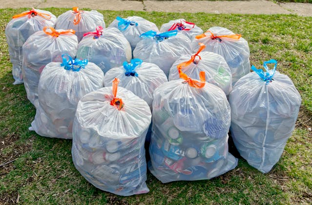 A Bunch of Full Trash Bags Standing on the Grass